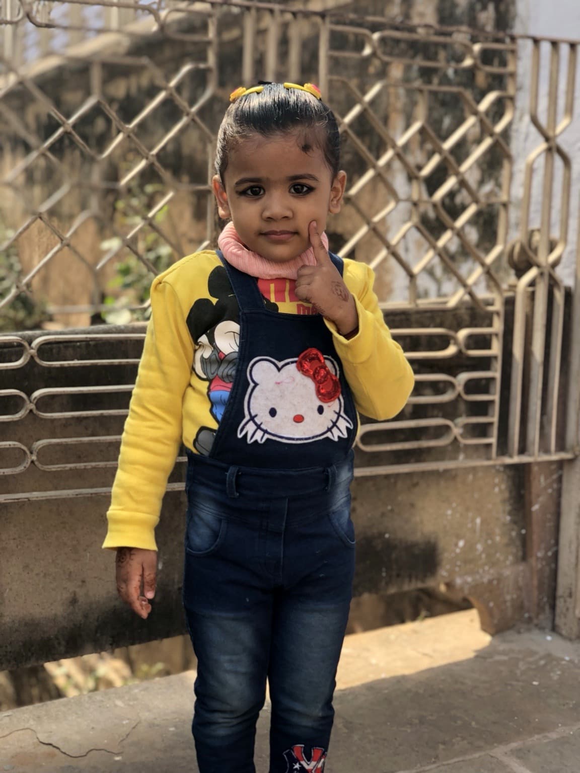 A young girl in yellow and dark blue clothing stands for a portrait in Varanasi, 2019
