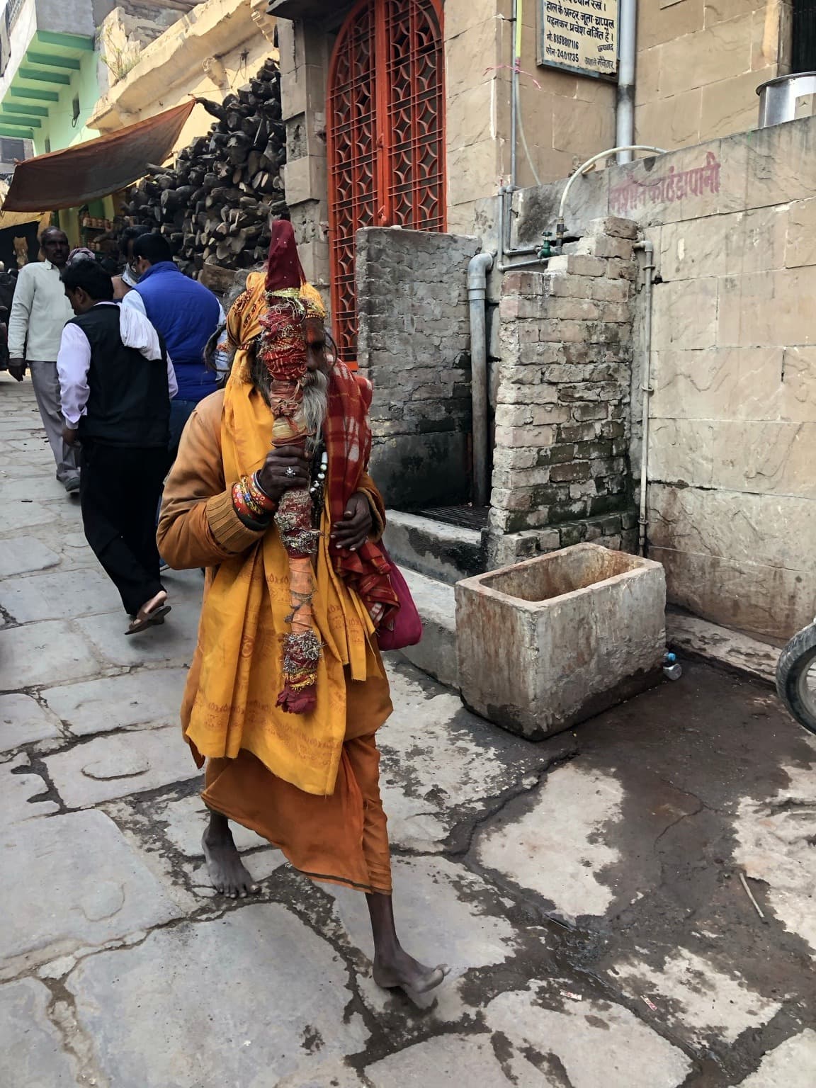 A saffron-robed man walks through a narrow stone lane in Varanasi, 2019