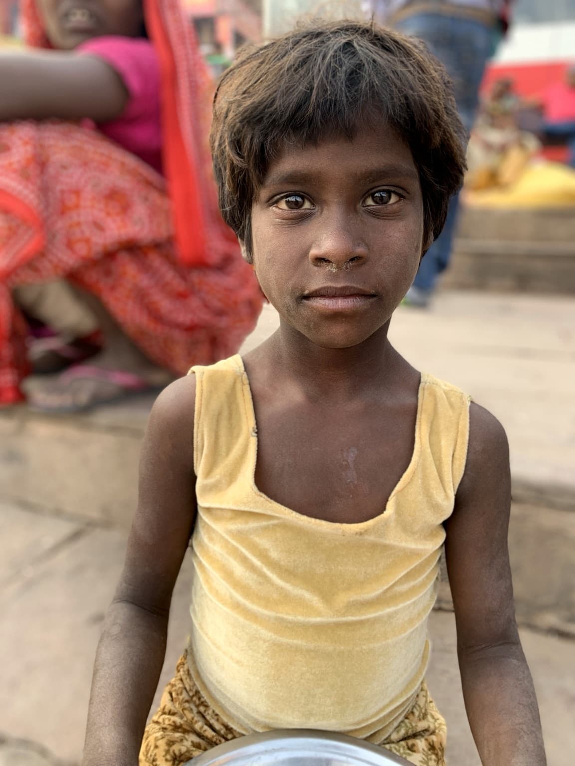 A child looks directly toward the camera in a close portrait on the ghats of Varanasi, 2019.