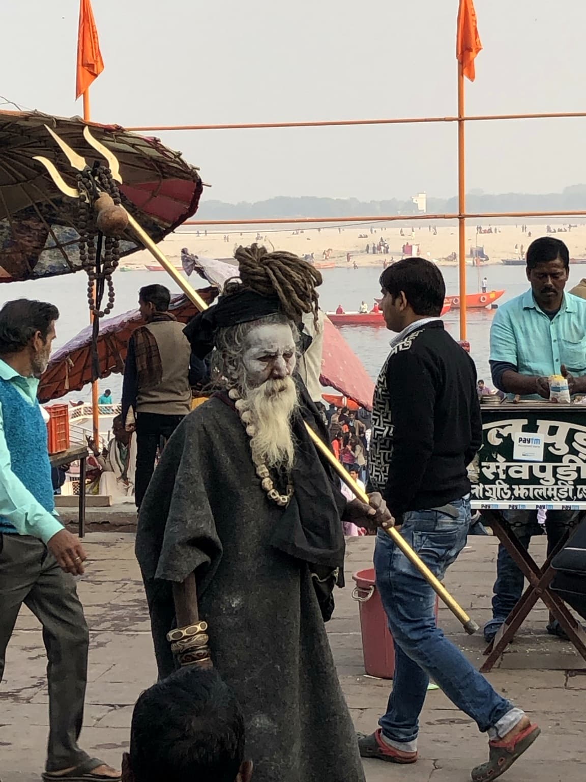 A sadhu is photographed within the surrounding riverfront environment on the ghats of Varanasi, 2019.