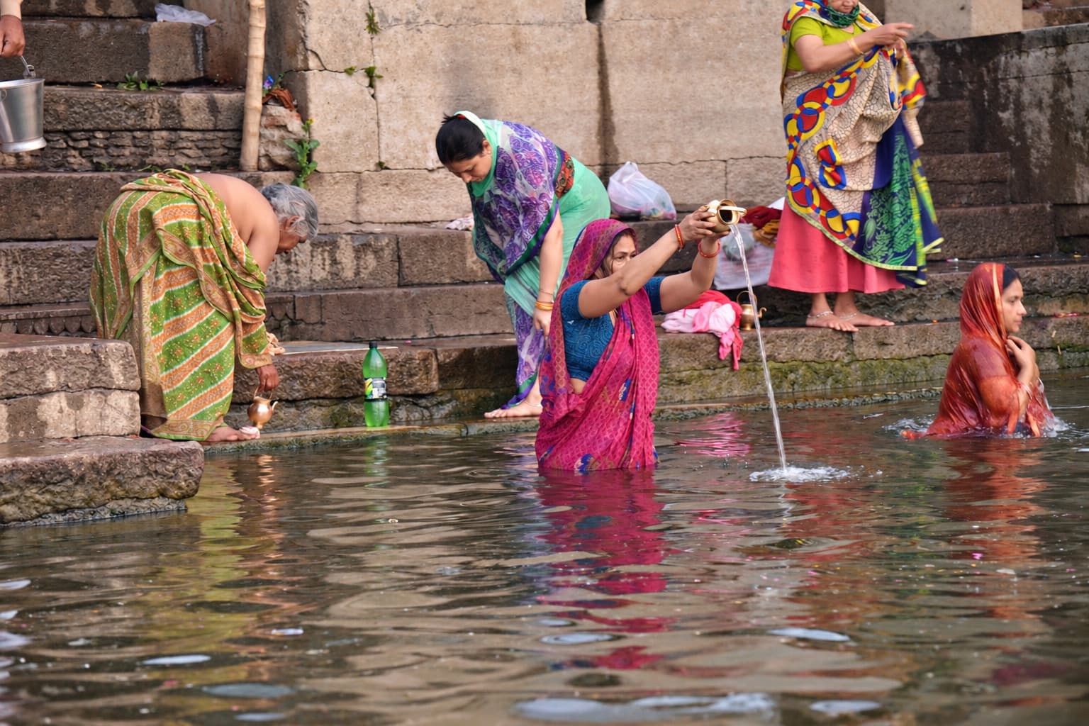 Women in vivid saris bathe, wash and dress beside the Ganges in Varanasi, 2019