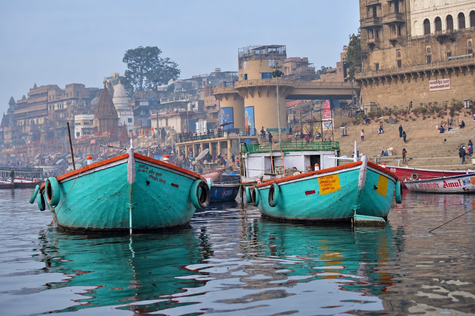 Turquoise wooden boats and their reflections form a layered pattern on the Ganges in Varanasi, 2019