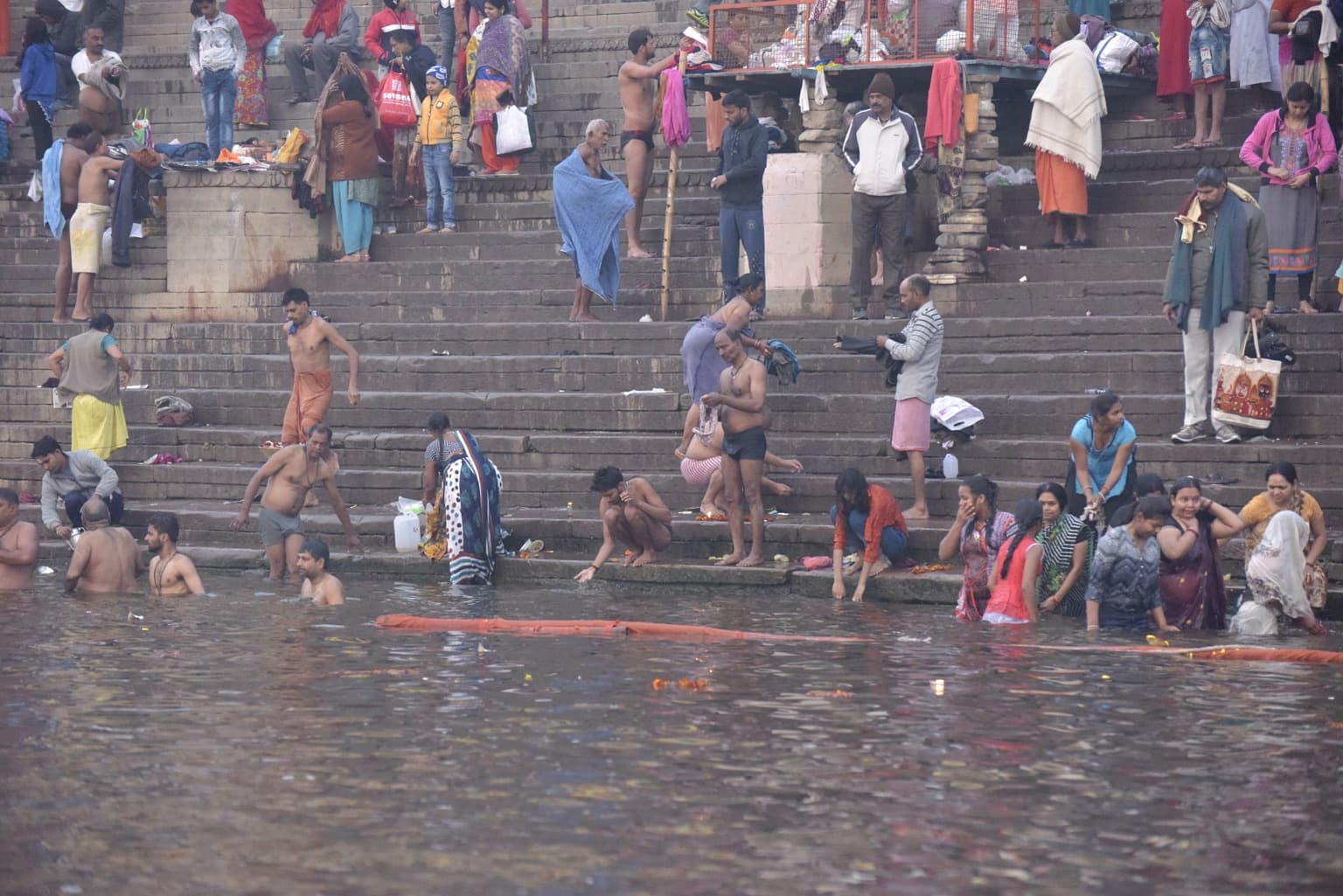 Men and women bathe, wash and prepare clothing along broad stone steps at the edge of the Ganges in Varanasi, 2019