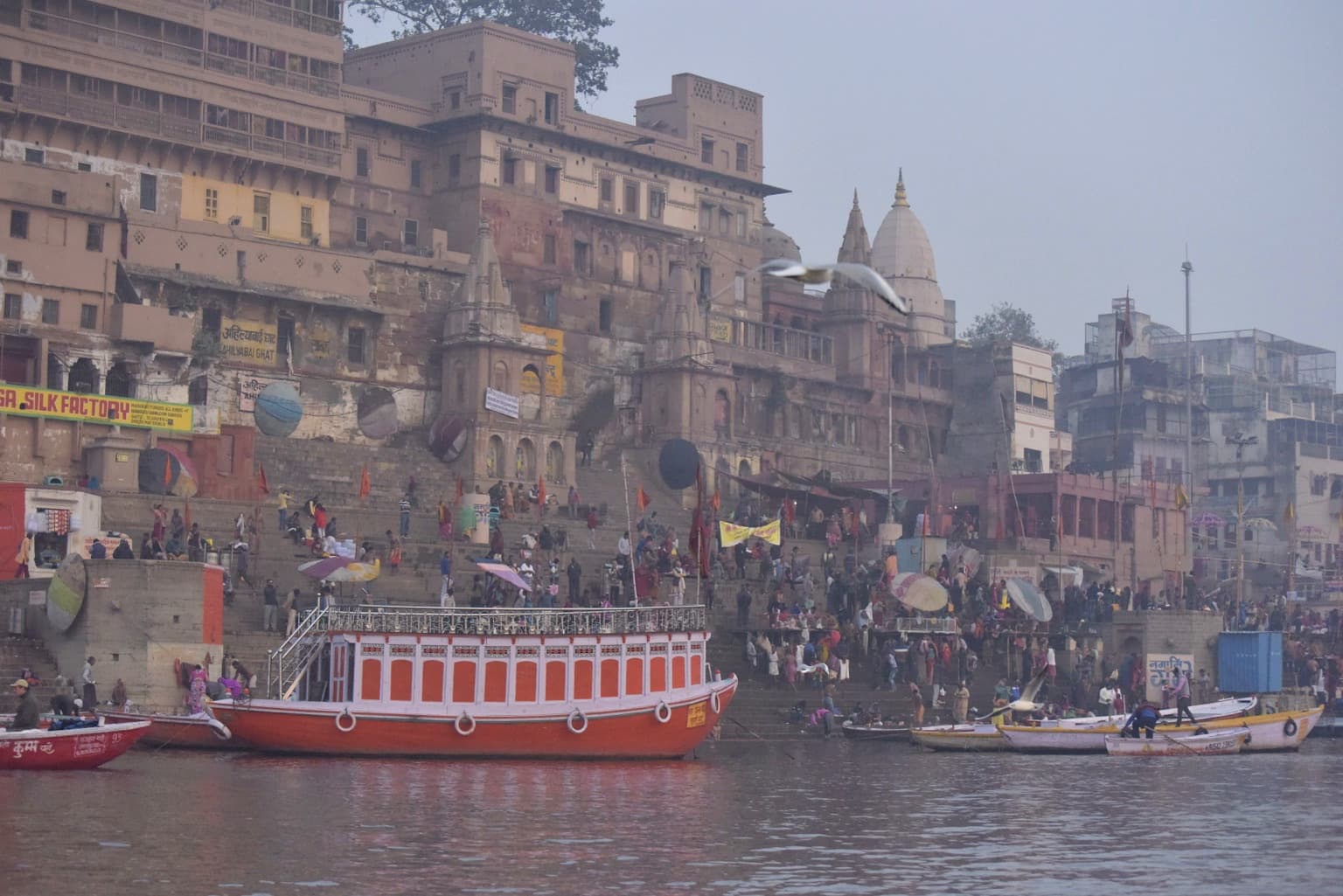 Riverfront buildings, temple spires and moored boats rise through the haze along the Ganges in Varanasi, 2019