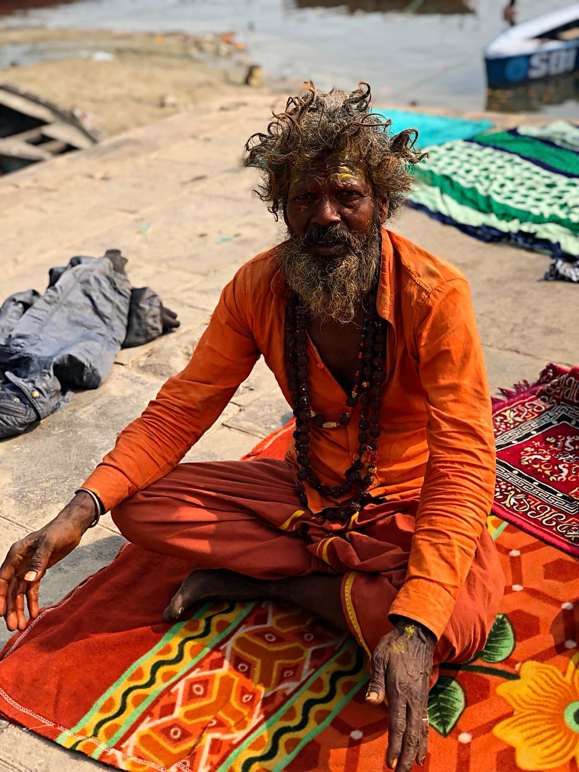The same orange-robed sadhu faces the camera directly on the ghats of Varanasi, 2019