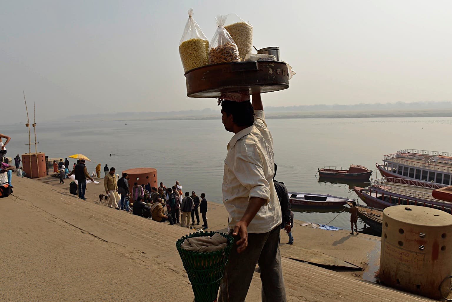 A vendor carries a large tray of snacks through the ghats of Varanasi, 2019