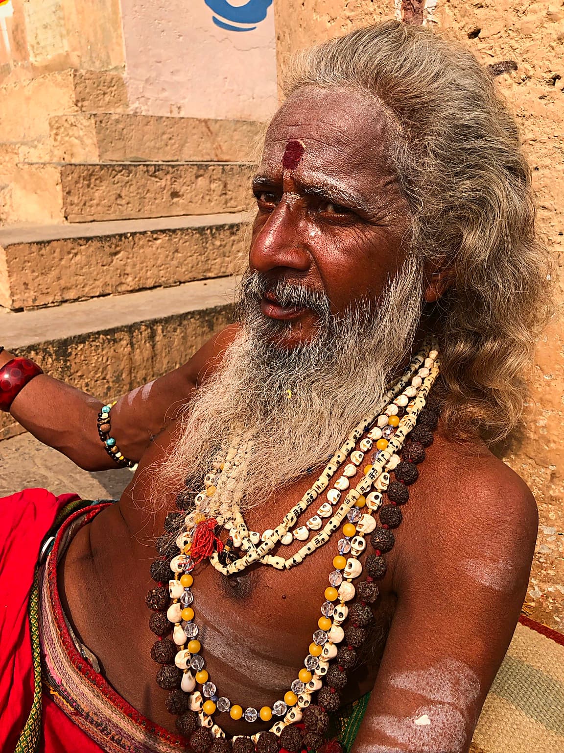 A close portrait shows a long-haired sadhu in a calm attentive moment on the ghats of Varanasi, 2019
