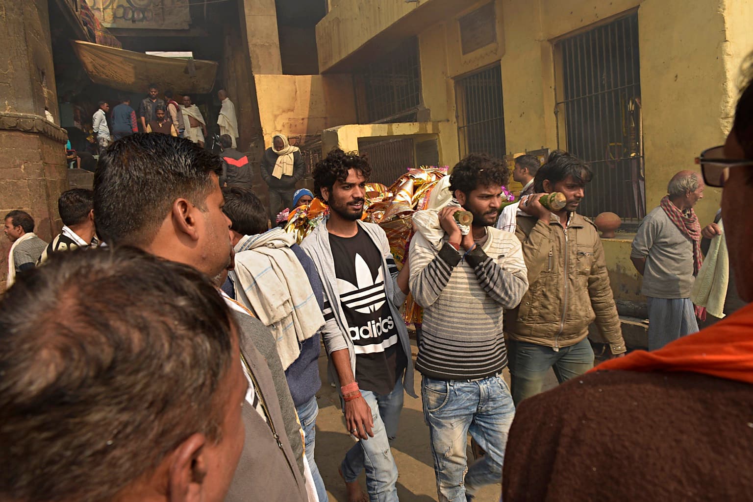 Men carry a wrapped bier through a crowded passage on the ghats of Varanasi, 2019