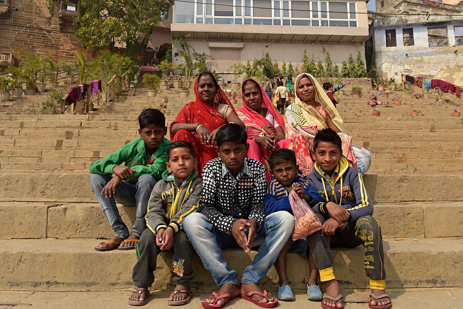 A group of women and children pose together on the broad ghat steps of Varanasi, 2019