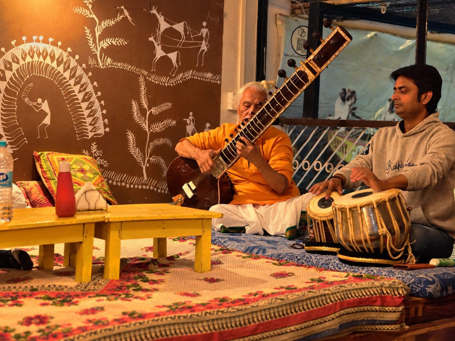 A sitar player and tabla player perform together in a warmly lit room in Varanasi, 2019