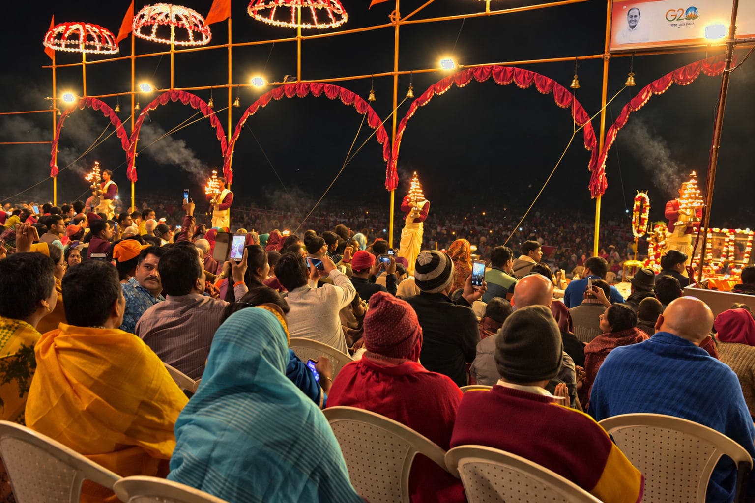 A line of priests holds flaming lamps during evening Ganga aarti before a dense crowd in Varanasi, 2019