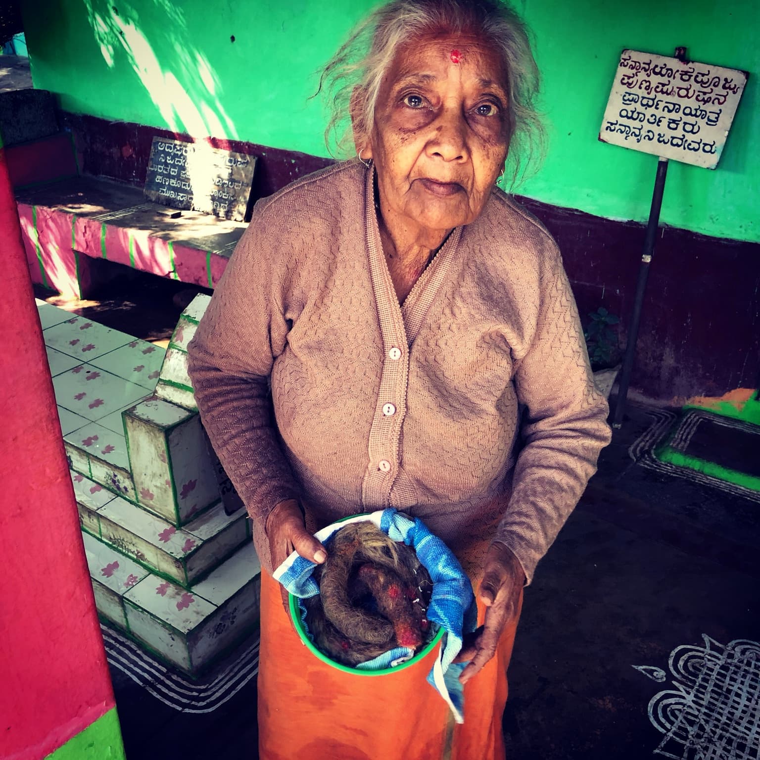 Closer view of the woman holding a green bowl containing the long hair she had preserved.