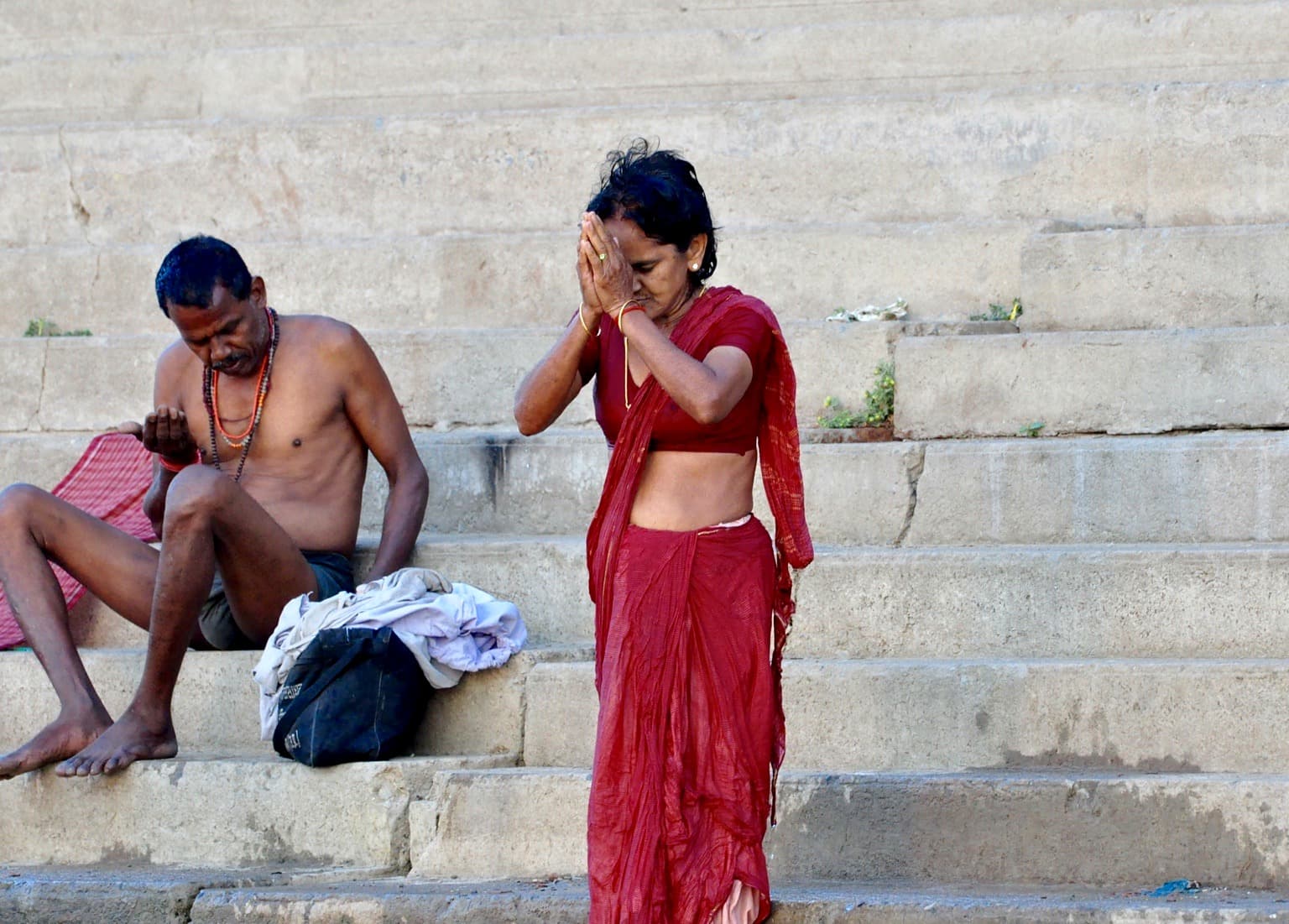 A woman in a red sari praying beside the Ganges in Varanasi, photographed in 2014