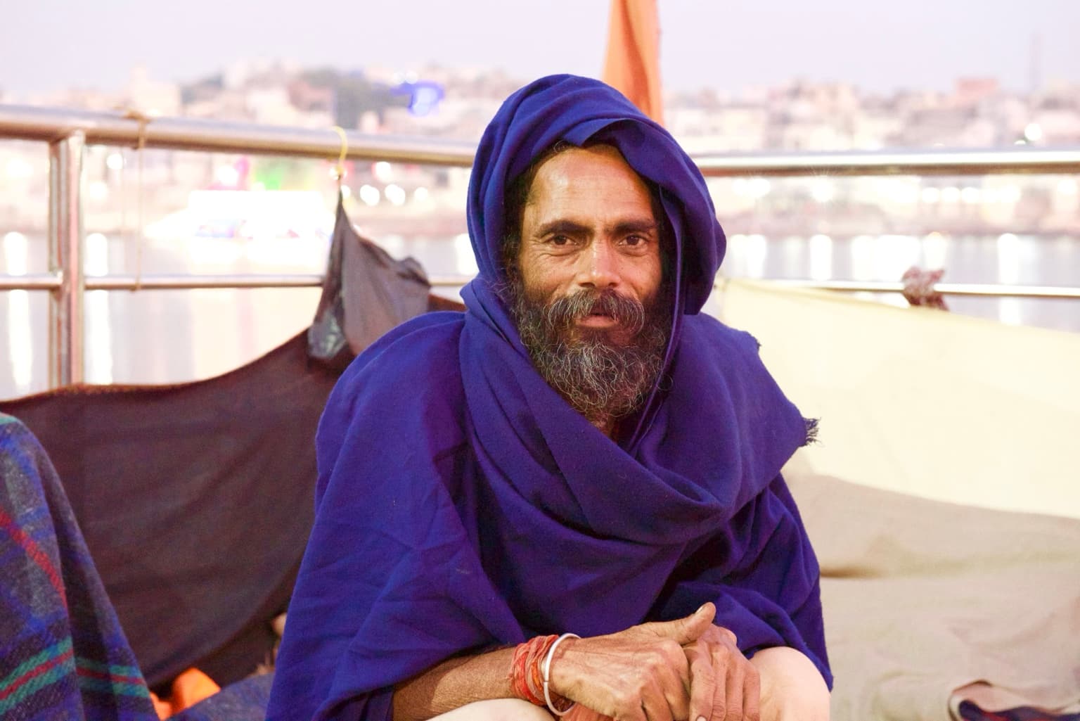 Portrait of the man in a deep blue shawl seated beside Pushkar Lake.