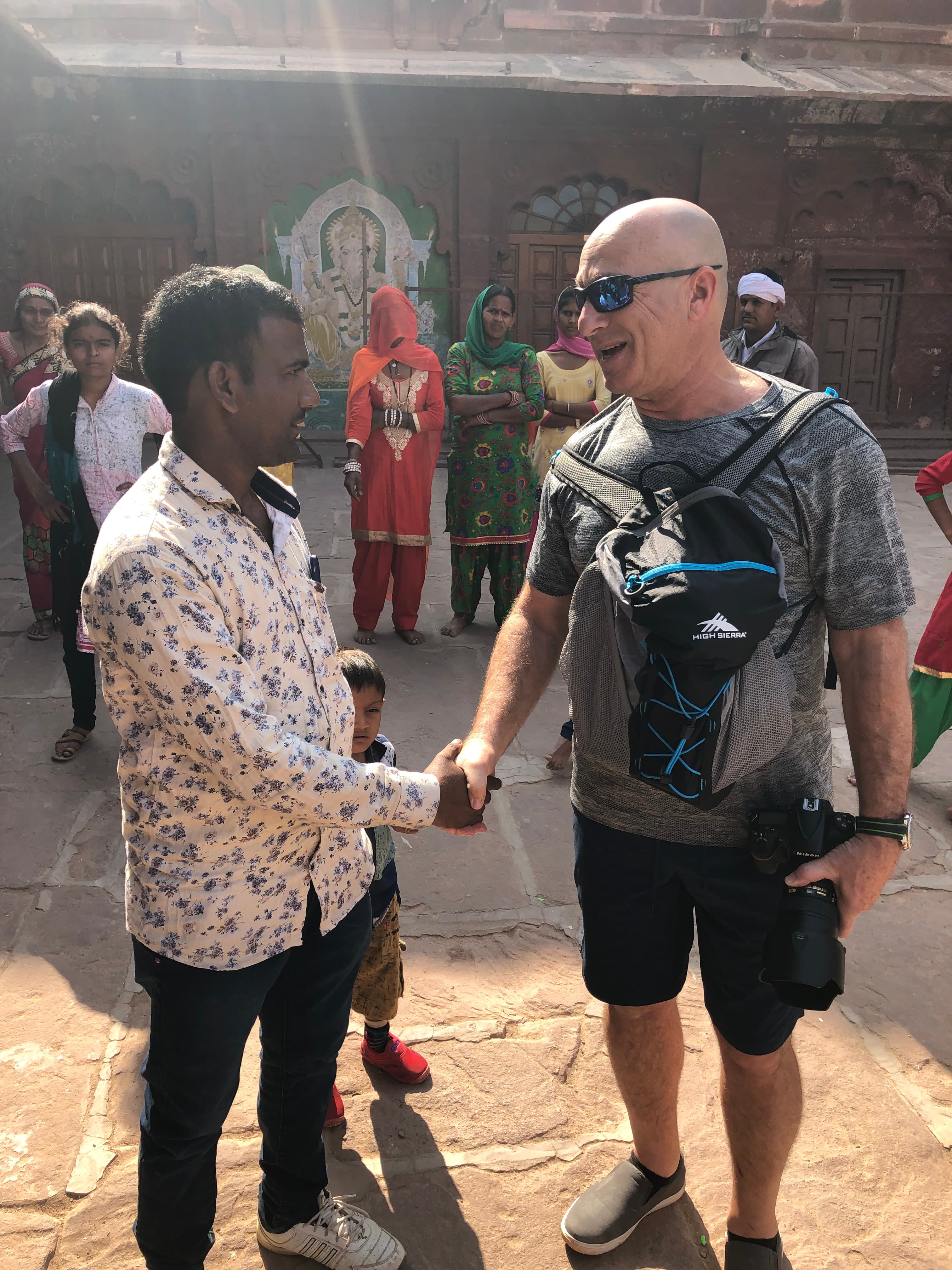 Brian Silver shaking hands with a man, his camera hanging at his chest.