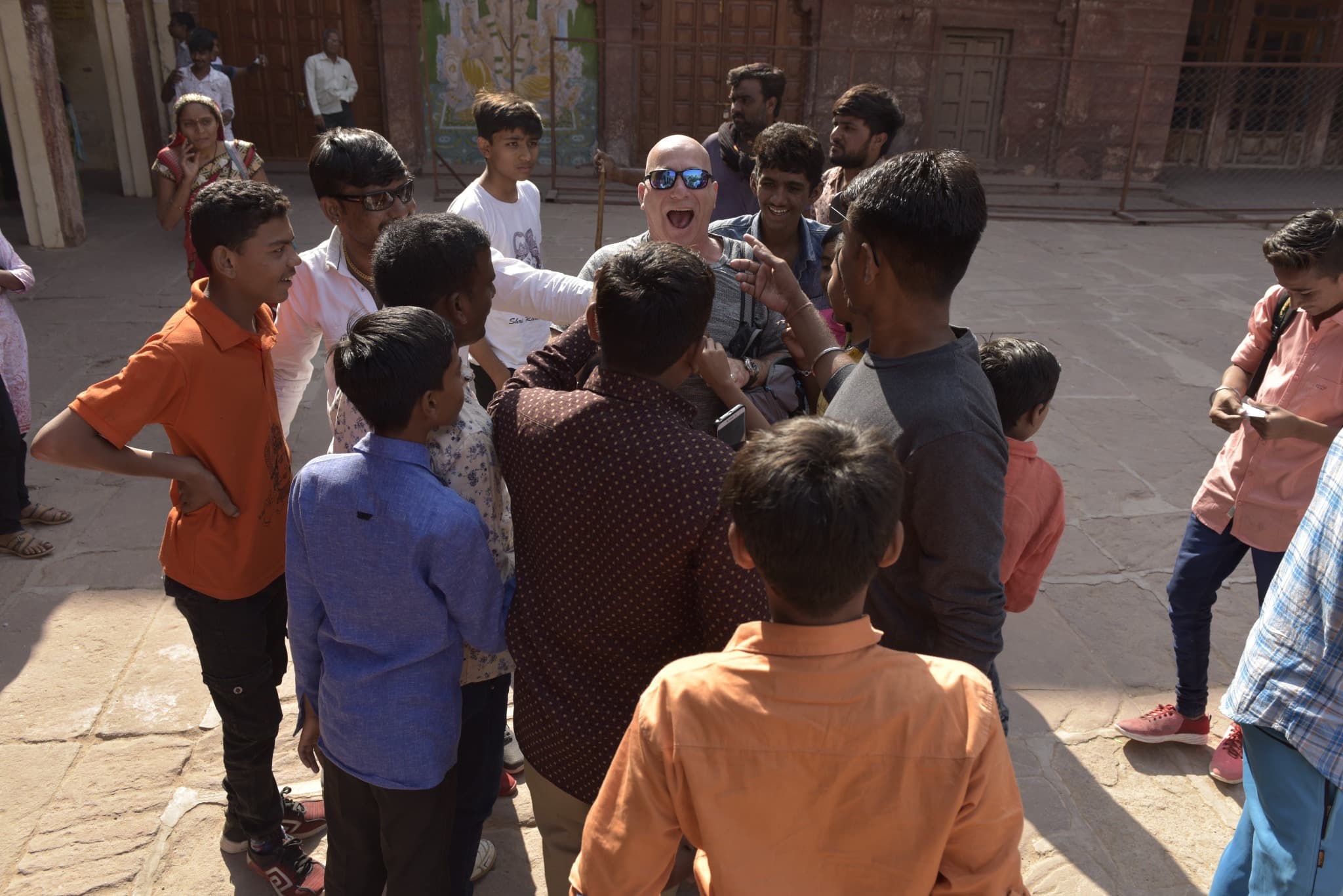 Brian Silver surrounded by people in a courtyard, smiling as phones are raised.