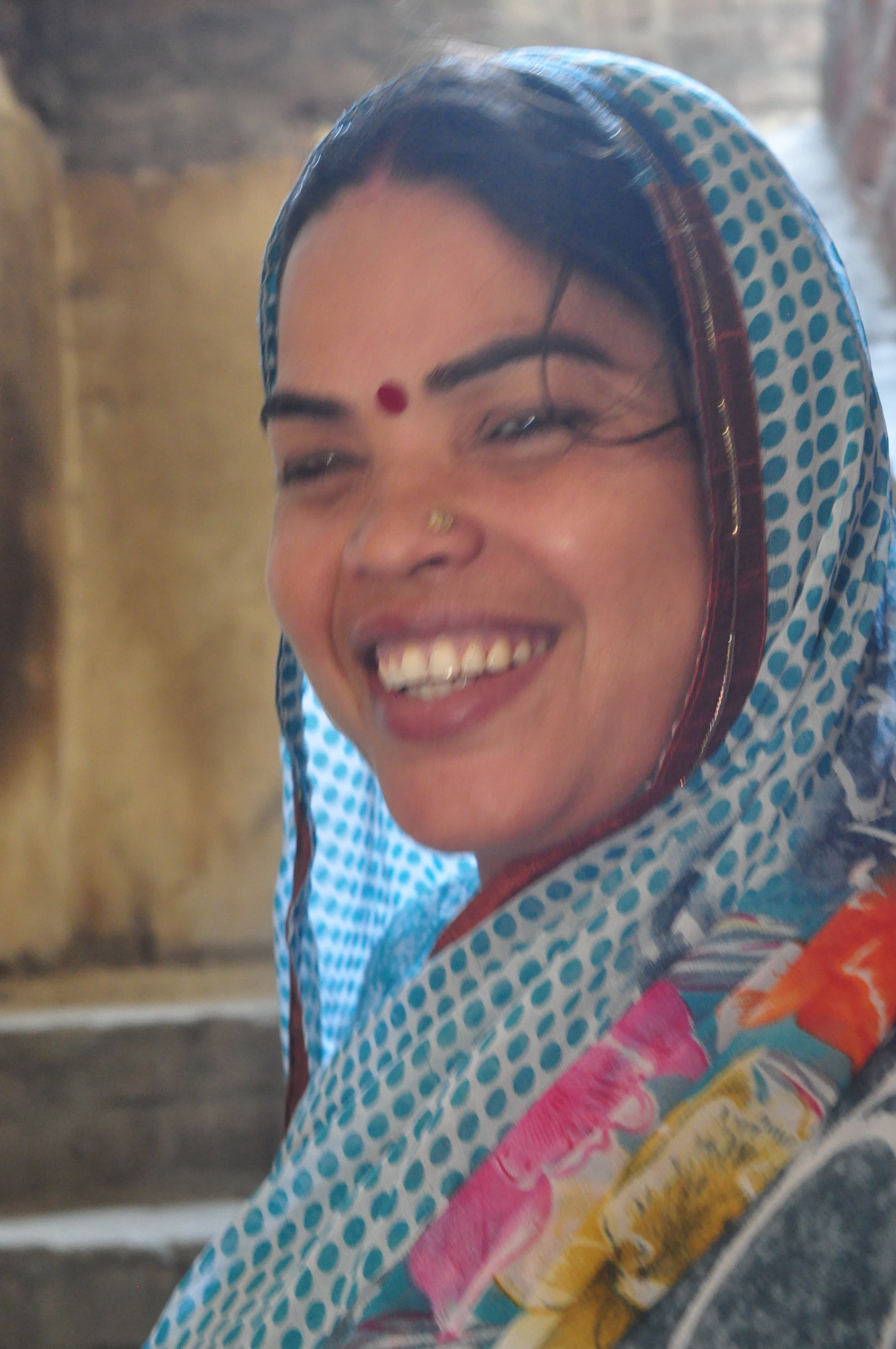 A smiling woman wearing a patterned sari at Baba's home.