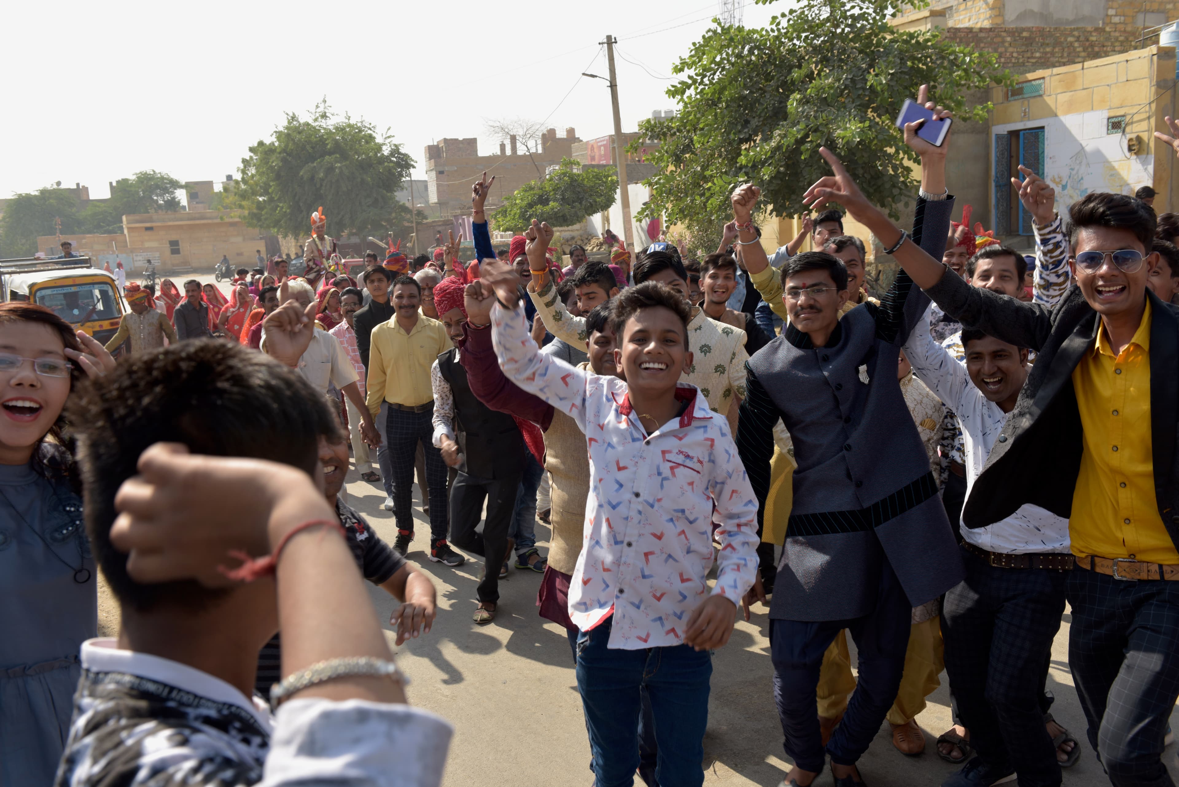 Young people smiling and raising their arms during the wedding procession.