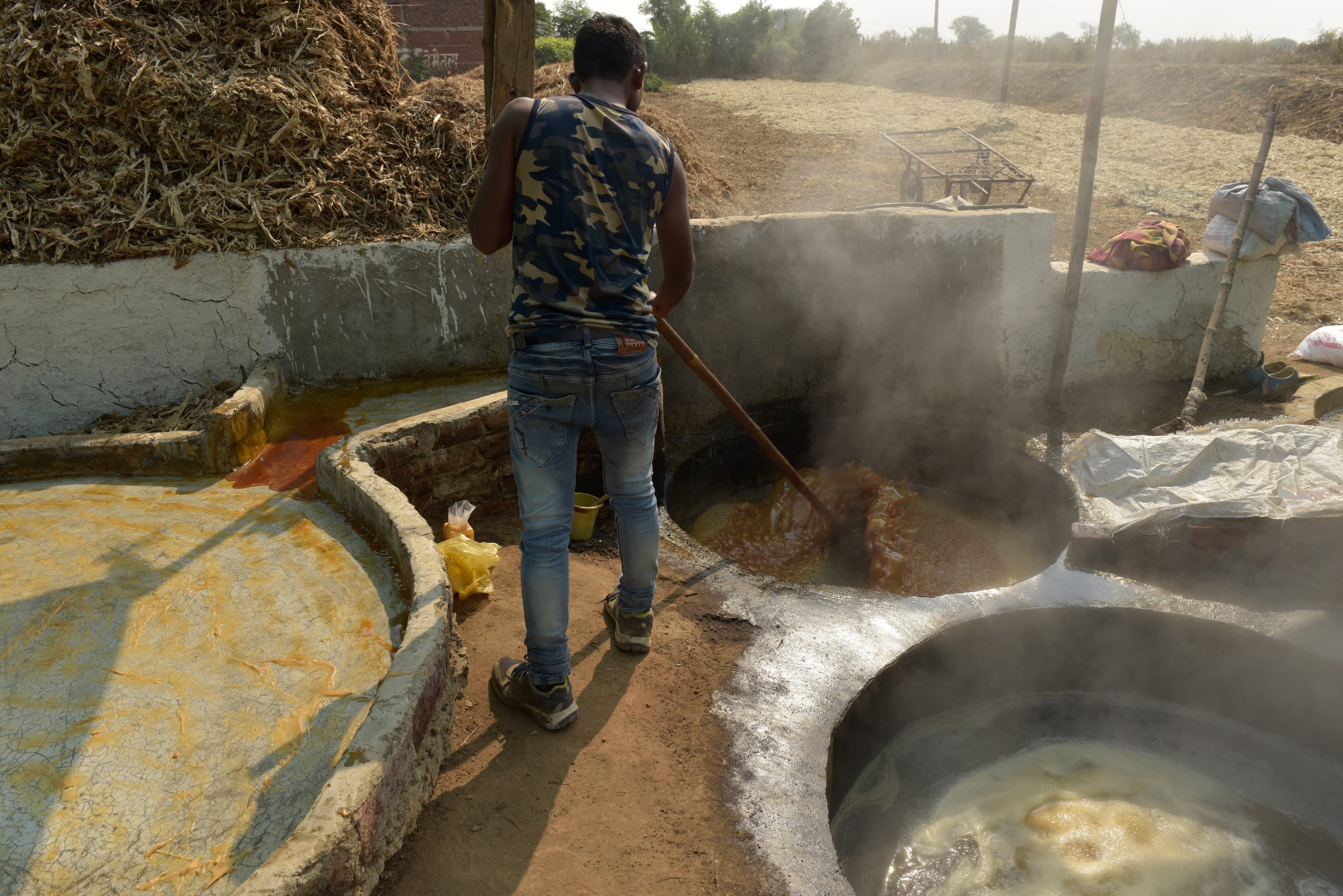 Worker stirring material in a large steaming vessel at the production site.