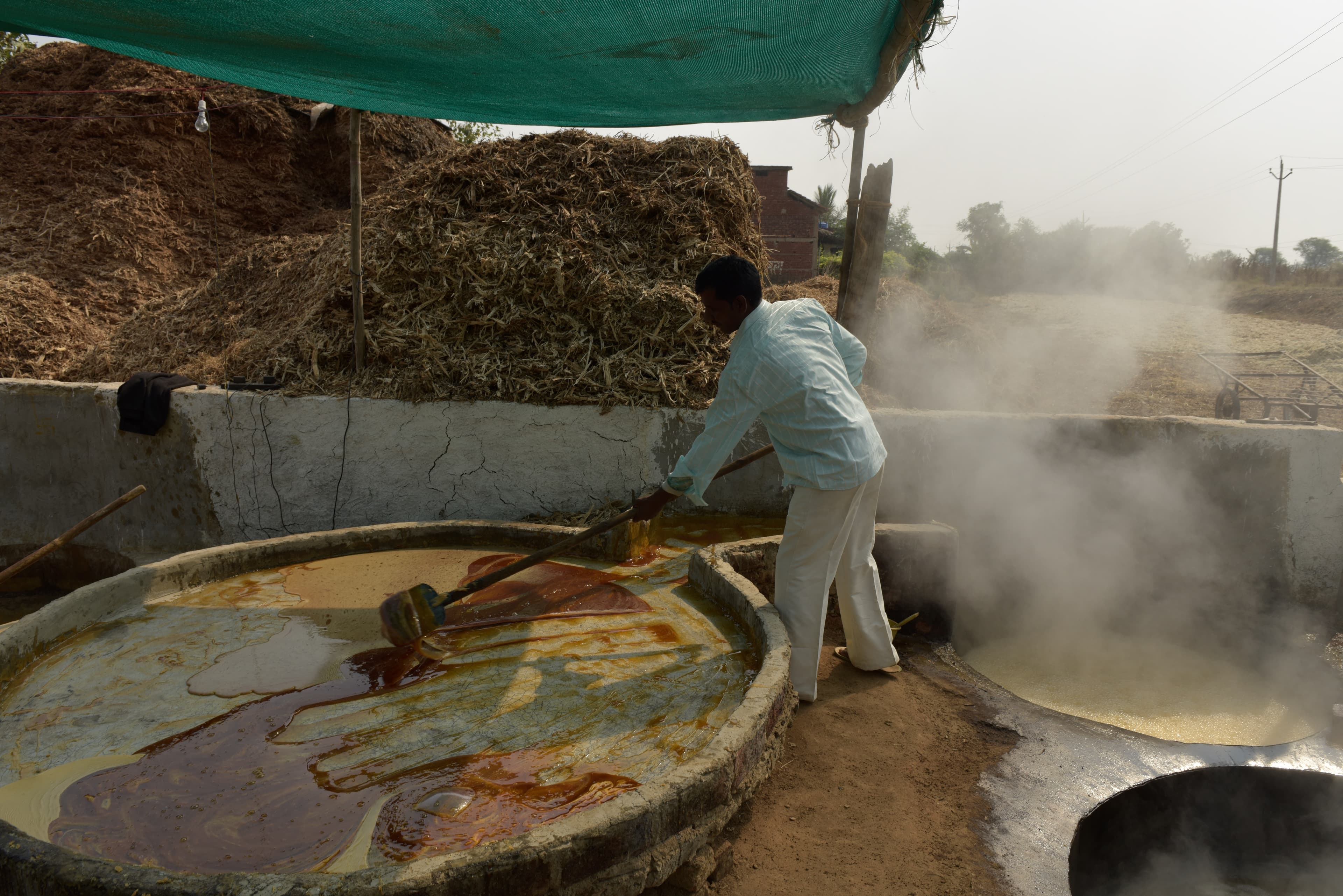 Worker moving thickened liquid across a large shallow processing pan.
